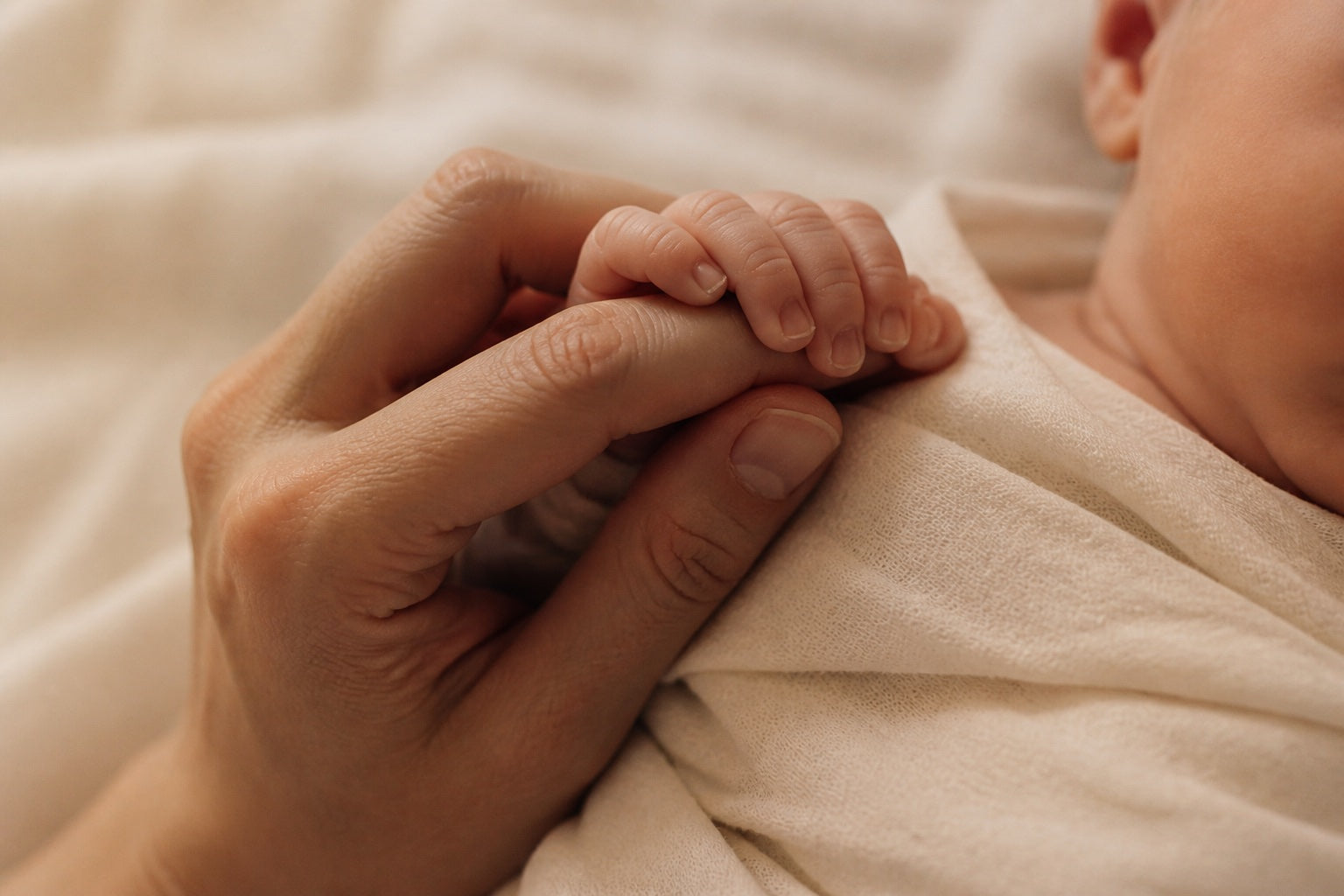 A newborn’s tiny hand holding a parent’s finger.